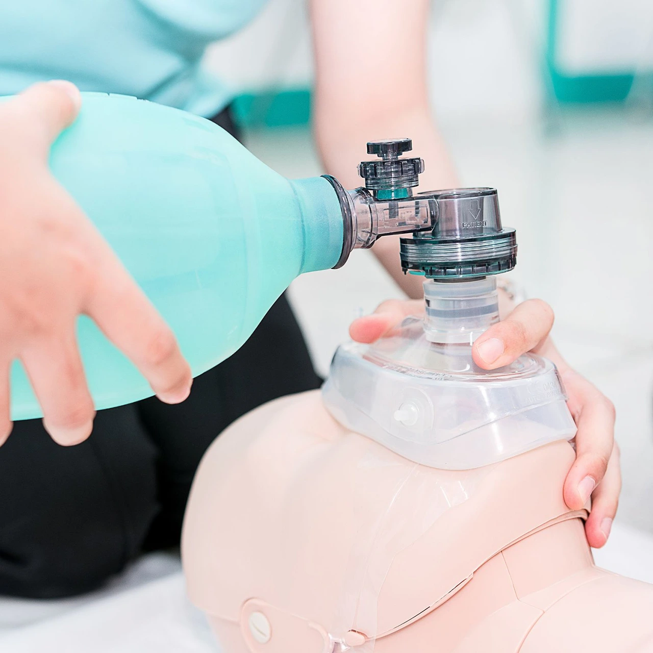 Person using a bag valve mask on a CPR training dummy.