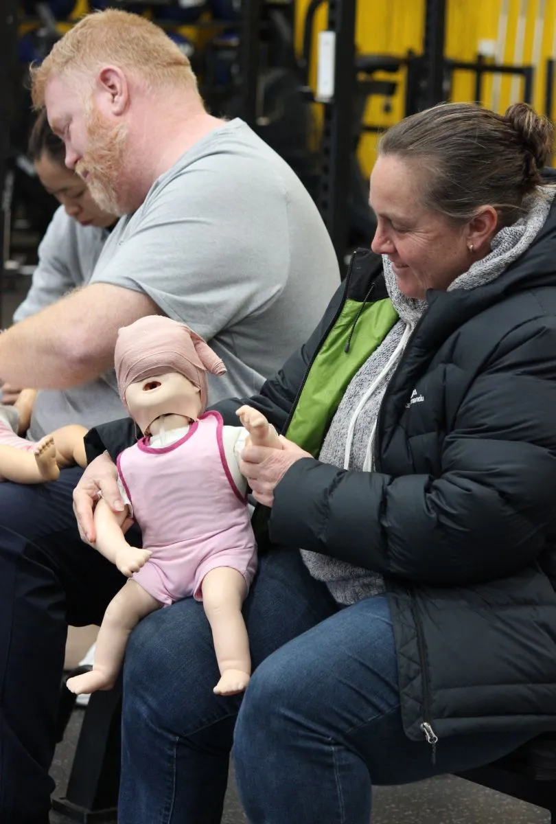 Participants practice skills using infant CPR dolls during training.
