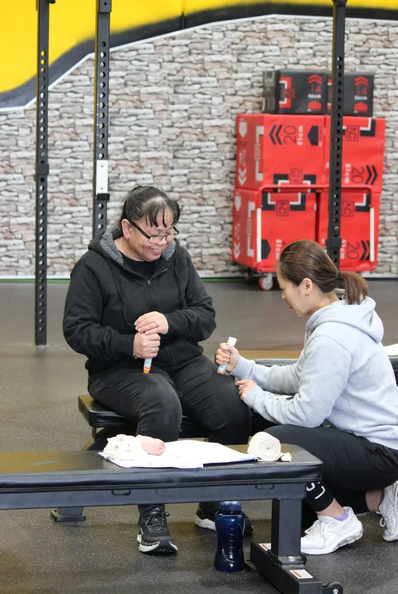Two women engage in a fitness training session with equipment.