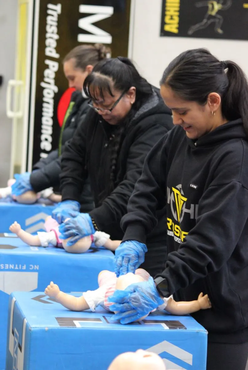 Participants practicing CPR techniques on dolls during a training session.