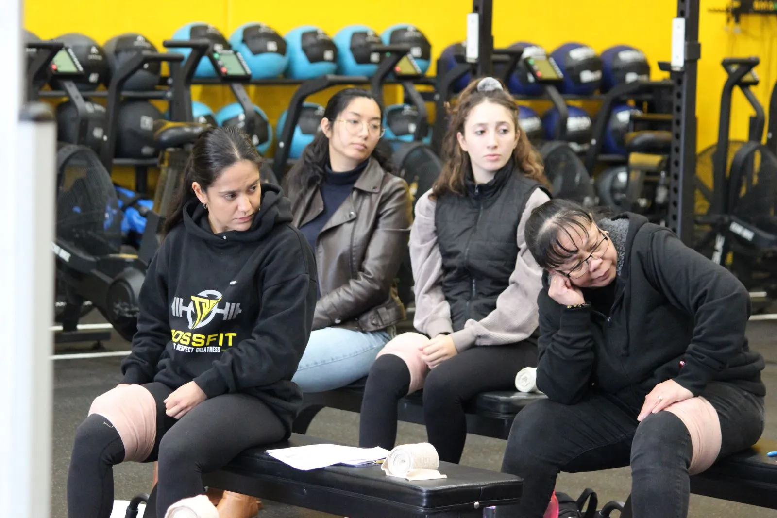 Group of women seated in a gym, focused and listening intently.