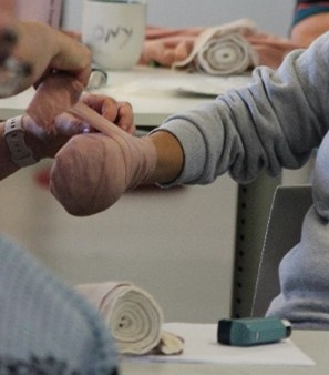 A person wrapping a bandage around another's hand in a training session.