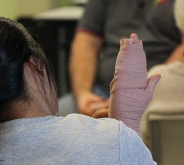 A person with a bandaged hand gesturing during a discussion.