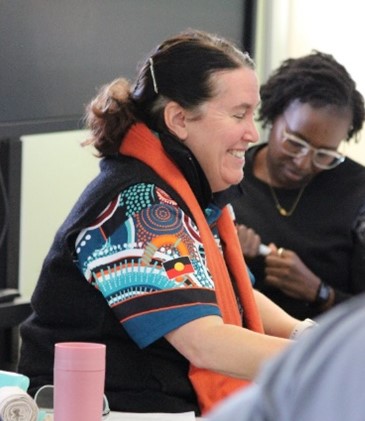 Woman with a colorful shirt and orange scarf engaged in discussion.