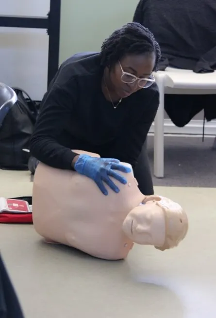Person practicing CPR techniques on a training mannequin.