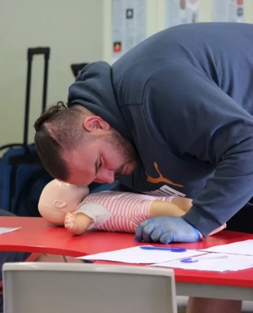 A person practices CPR techniques on a baby manikin.