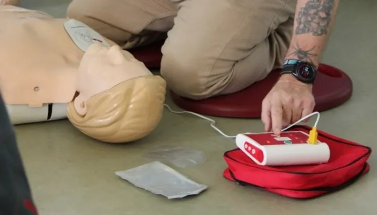 A person using an AED on a manikin during a CPR training session.
