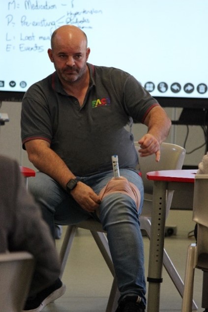 Instructor demonstrating a medical technique in a classroom setting.