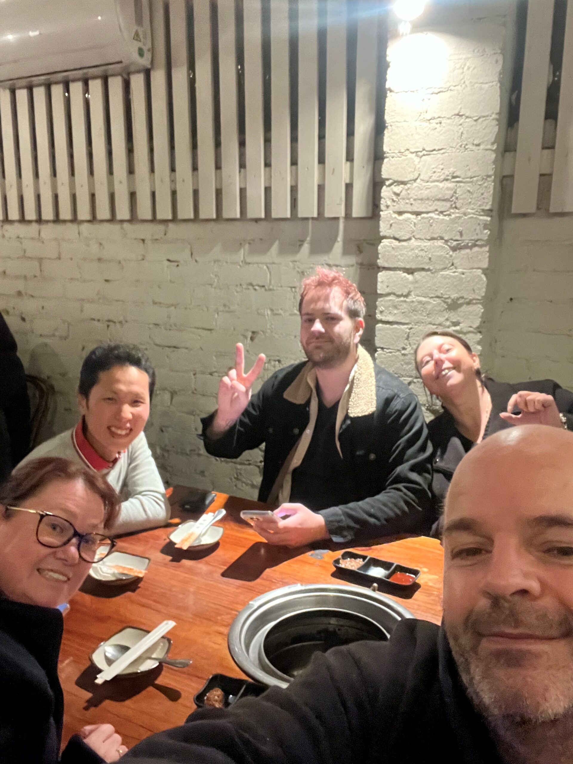 Group of friends enjoying a meal around a wooden table.
