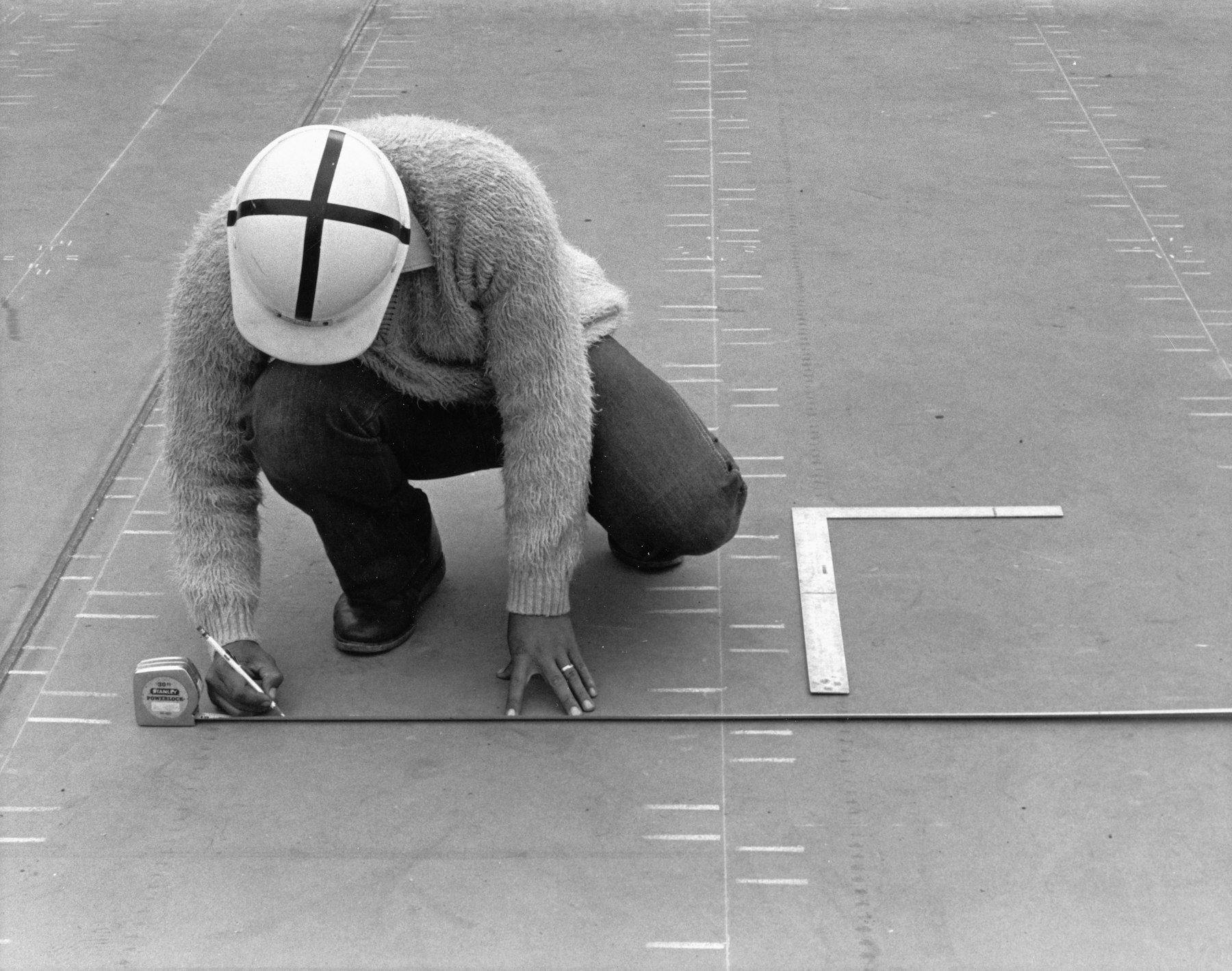 Construction worker using a tape measure to check dimensions during site setup.