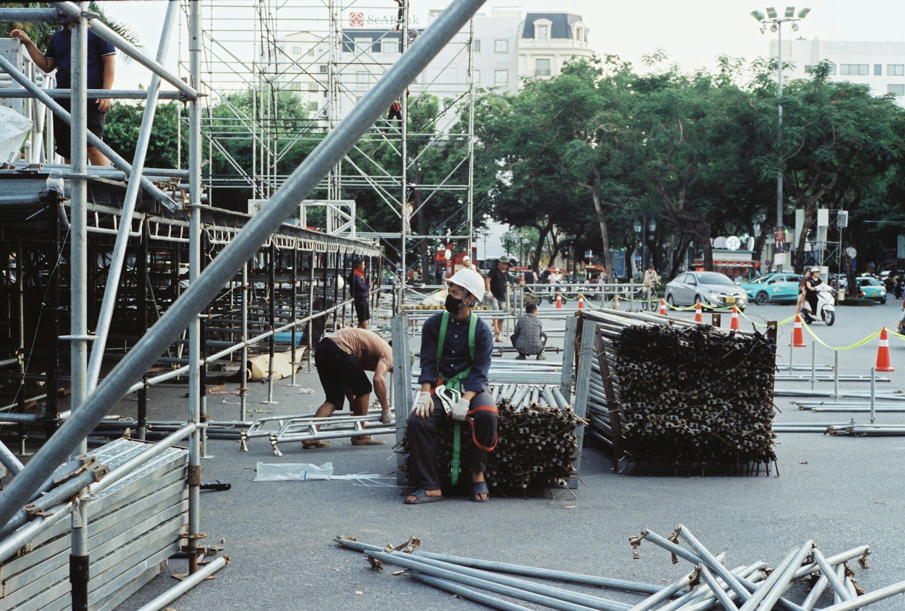 Workers setting up scaffolding and organising scaffold components at a construction site.